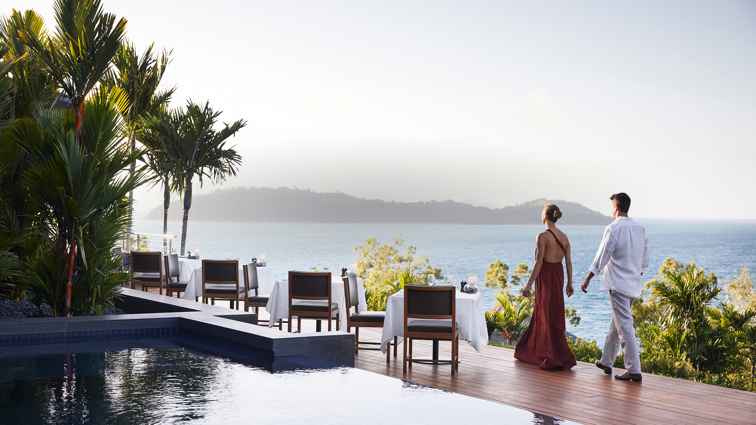 qualia Resort Couple Walking Through Outdoor Dinner Tables at Long Pavilion Restaurant with Whitsundays Views