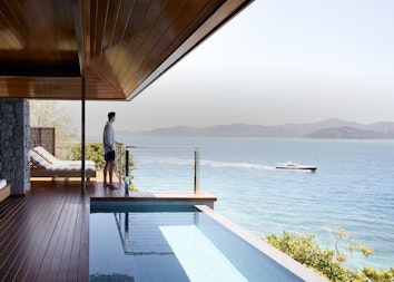 Man on qualia Windward Pavilion private deck with plunge pool looking out to luxury boat within view of the Whitsundays 