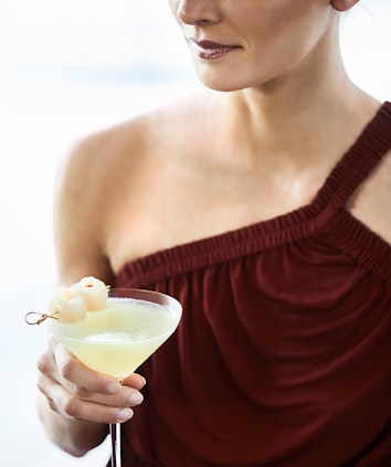 Close up of woman in maroon dress holding lychee martini cocktail at Long Pavilion bar at qualia