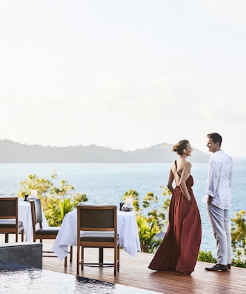 Couple standing by dinner table on Long Pavilion deck with views of the Whitsundays
