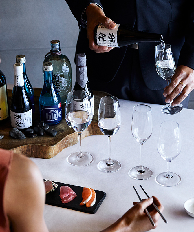 Sommelier pouring sake into glasses as part of Talk and Taste Sake and Sashimi experience at qualia resort Long Pavilion