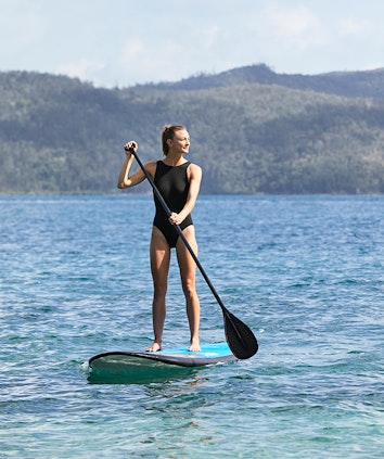 Woman enjoying qualia resort experience of stand up paddle boarding