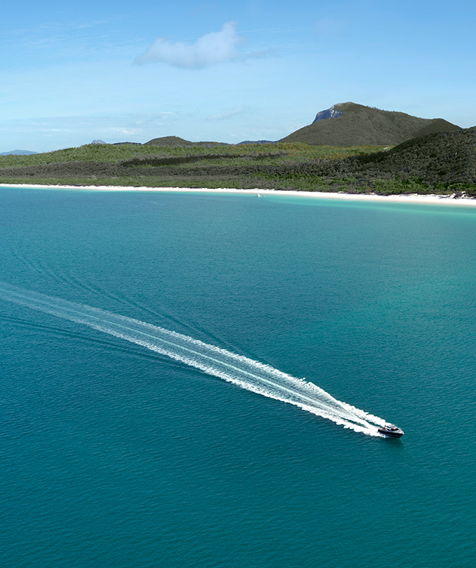 Aerial view of boat and its wake in the Whitsundays as part of qualia boating experience at Whitehaven Beach