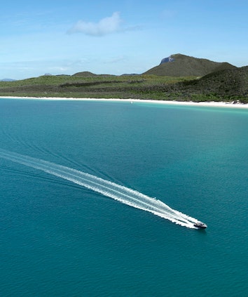 Aerial of boat leaving trail in water in front of Whitehaven Beach as part of qualia boating experience