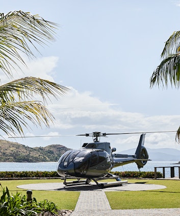 Helicopter landed at private helipad surrounded by gardens and Whitsunday views