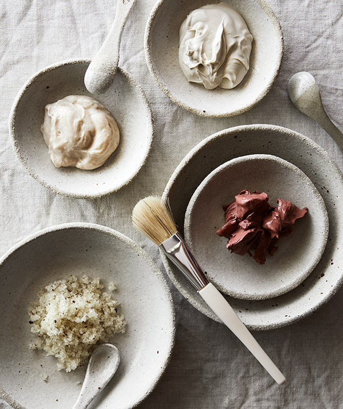 Small bowls of Spa qualia products including body scrubs, mud and cream with application spoons and brush.
