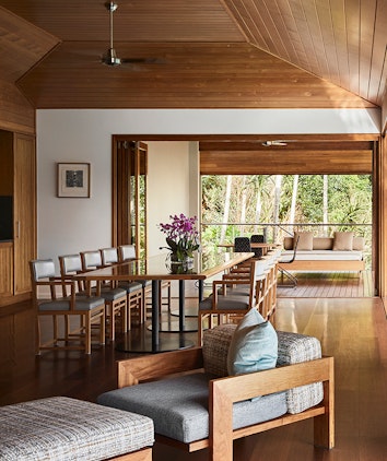 Armchair, ottoman, and dining table with ten chairs inside qualia resort's Beach House