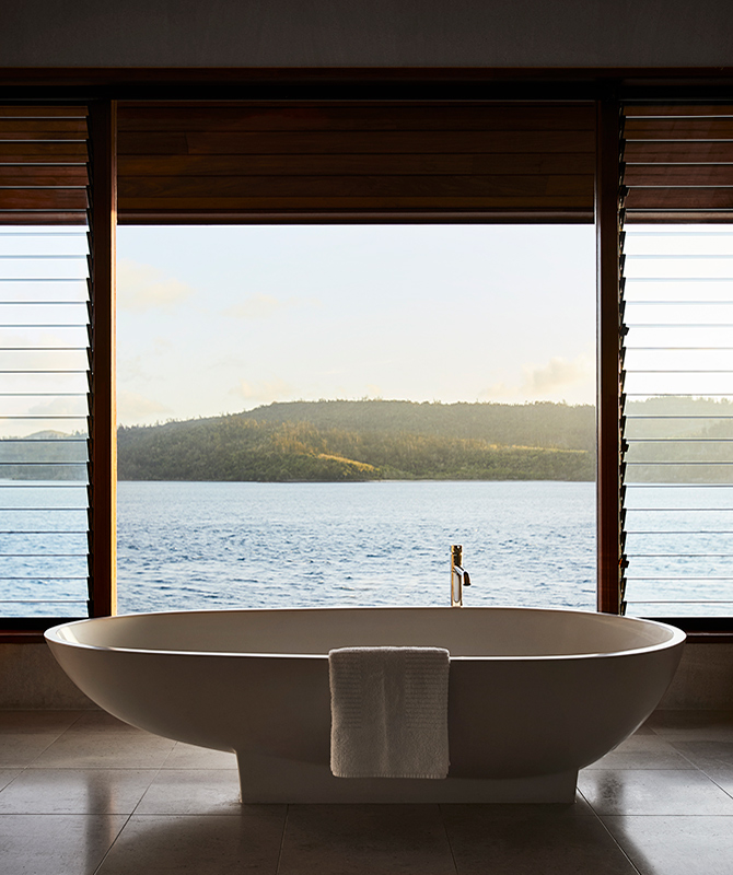 Raised modern bathtub in qualia Windward Pavilion with views of Whitsundays through window