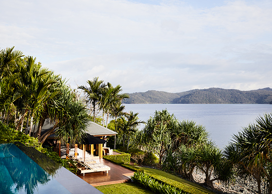 qualia resort view of a covered Beach House deck with sun lounges and Whitsundays views surrounded by palm trees