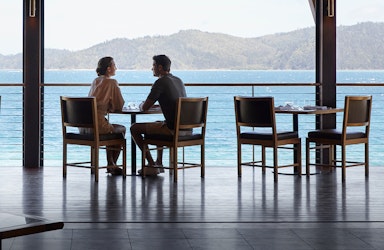 Couple sitting at Pebble Beach restaurant table for lunch with views of Whitsundays