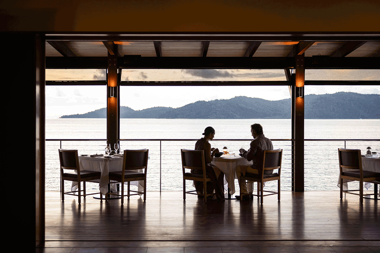 Couple sitting at Pebble Beach restaurant table for lunch with views of Whitsundays