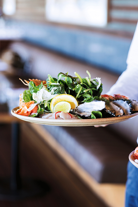 Couple sitting at Pebble Beach restaurant table for lunch with views of Whitsundays