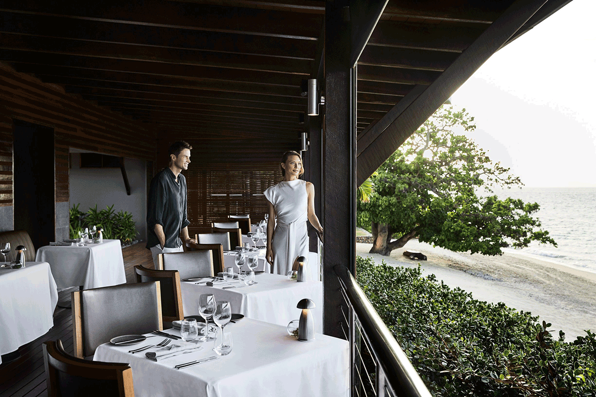 Couple sitting at Pebble Beach restaurant table for lunch with views of Whitsundays