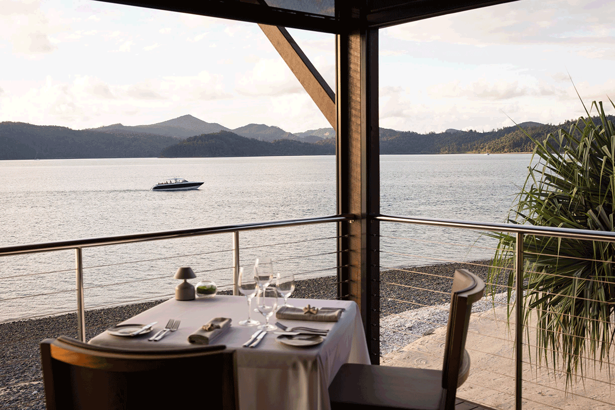 Couple sitting at Pebble Beach restaurant table for lunch with views of Whitsundays