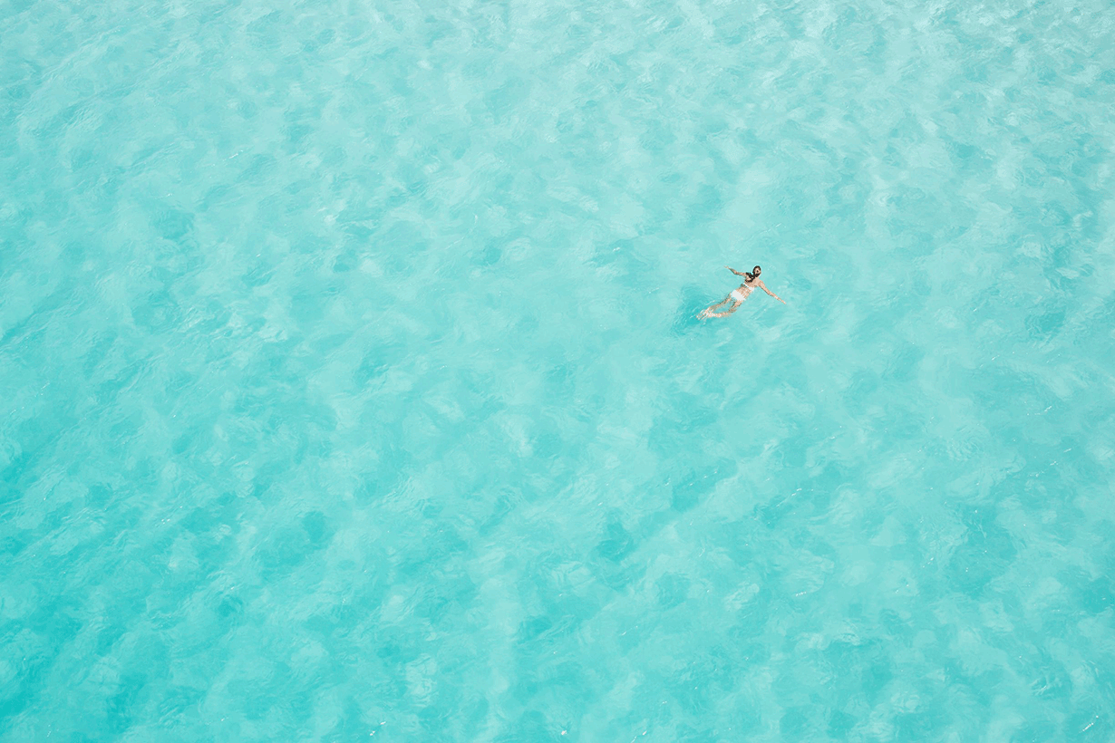 Aerial view of people enjoying waves breaking into the sand at Whitehaven Beach 