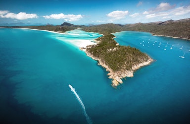 Aerial view of boat and its wake in the Whitsundays as part of qualia boating experience at Whitehaven Beach