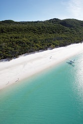Aerial view of people enjoying waves breaking into the sand at Whitehaven Beach 