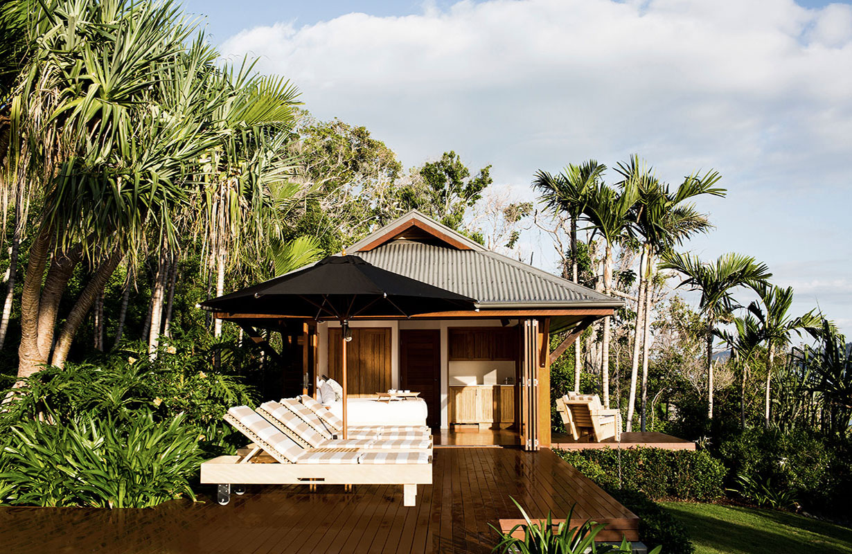 View of white bathtub and stone wall at qualia Beach House bathroom