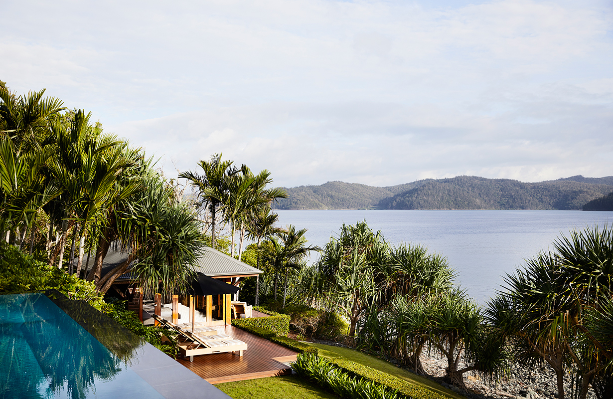 View of white bathtub and stone wall at qualia Beach House bathroom