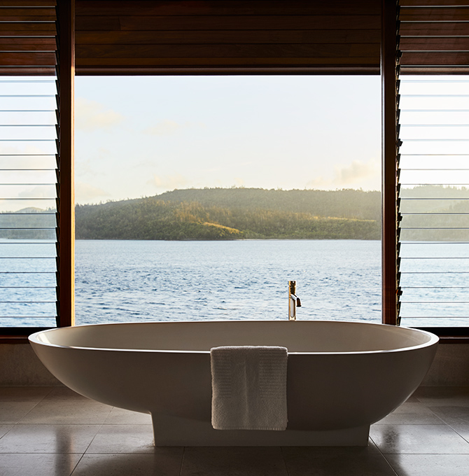 Raised modern bathtub in qualia Windward Pavilion with views of Whitsundays through window