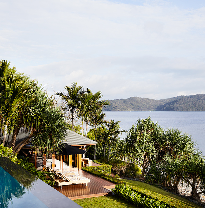 qualia resort view of covered Beach House deck with sun lounges and Whitsundays views surrounded by palm trees