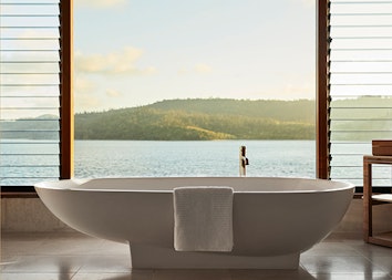 Raised modern bathtub in qualia Windward Pavilion with views of Whitsundays through window
