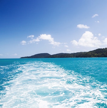 qualia resort boating experience with the wake of a boat across the bright blue Whitsundays waters 
