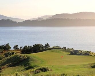 qualia view of red pin on Dent Island Golf course with sunlight pouring from the Whitsundays