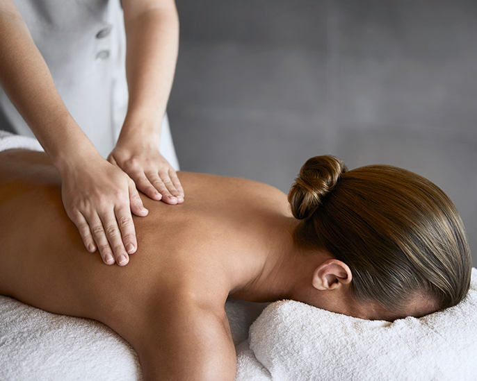 Woman receiving a back massage by spa therapist as part of spa qualia treatment