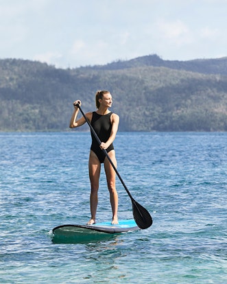 Woman enjoying qualia resort experience of stand up paddle boarding