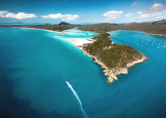Aerial view of boat and its wake in the Whitsundays as part of qualia boating experience at Whitehaven Beach
