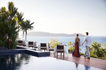 qualia Resort Couple Walking Through Outdoor Dinner Tables at Long Pavilion Restaurant with Whitsundays Views