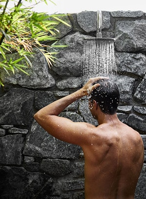 Man enjoying outdoor shower facing stone wall at spa qualia 