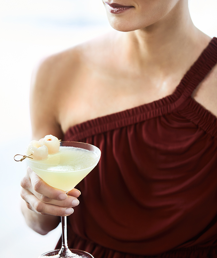 Close up of woman in maroon dress holding lychee martini cocktail at Long Pavilion bar at qualia