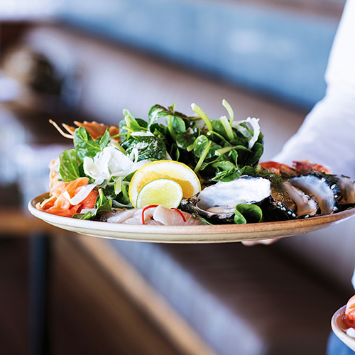 Waiter carrying seafood lunch dish at qualia resort restaurant Pebble Beach in the Whitsundays