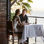 Couple enjoying wine and Whitsundays views at dinner table at qualia resort restaurant Pebble Beach 