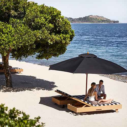 qualia resort guest couple sitting on sun lounges at Pebble Beach with Whitsundays views