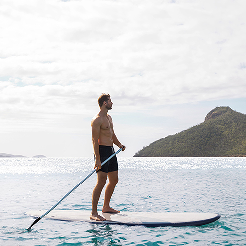 Man enjoying qualia resort experience of stand up paddle boarding at Catseye Beach
