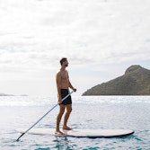 Man enjoying qualia resort experience of stand up paddle boarding at Catseye Beach