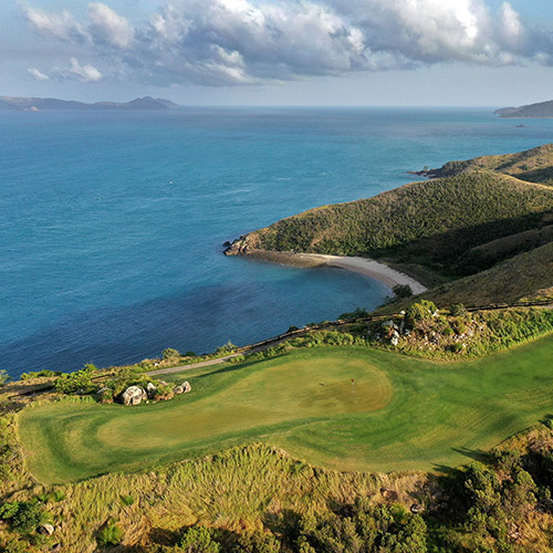 qualia aerial view of Dent Island Golf Course with rolling hills surrounded by Whitsundays
