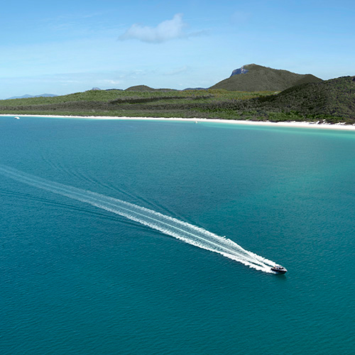 Aerial view of boat and its wake in the Whitsundays as part of qualia boating experience at Whitehaven Beach