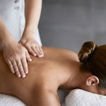 Woman receiving a back massage by spa therapist as part of spa qualia treatment