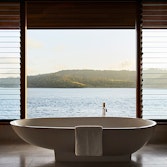 Raised modern bathtub in qualia Windward Pavilion with views of Whitsundays through window