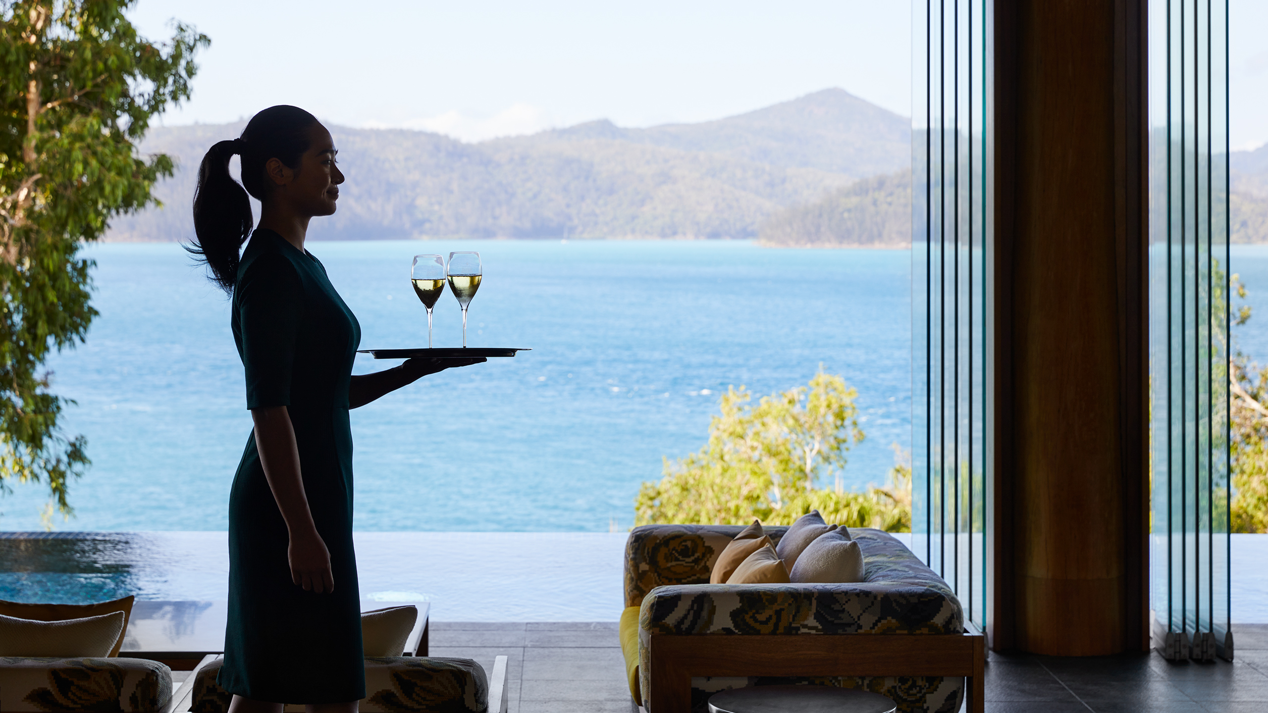 qualia Attendant in Long Pavilion Walking with Tray for Welcome Champagne Service