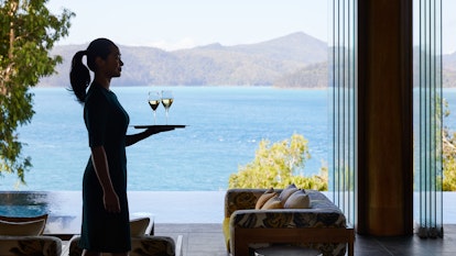 qualia Attendant in Long Pavilion Walking with Tray for Welcome Champagne Service