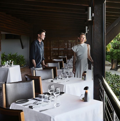 qualia Pebble Beach Restaurant With Man and Woman Standing By Tables Overlooking Beach