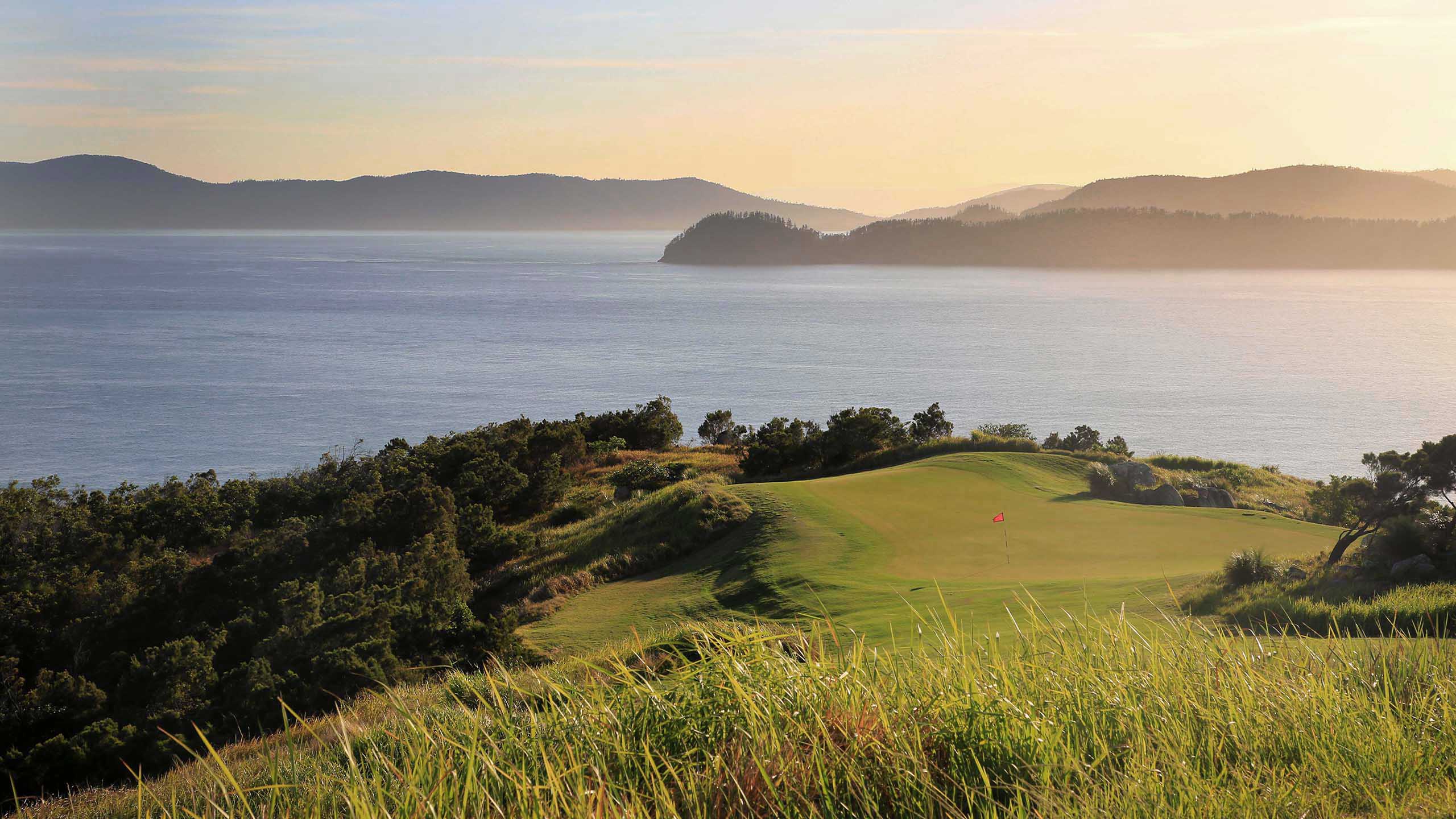 View of the Dent Island Golf Course hills with sunlight coming from across the Whitsundays 