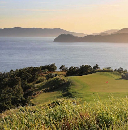 View of the Dent Island Golf Course hills with sunlight coming from across the Whitsundays 