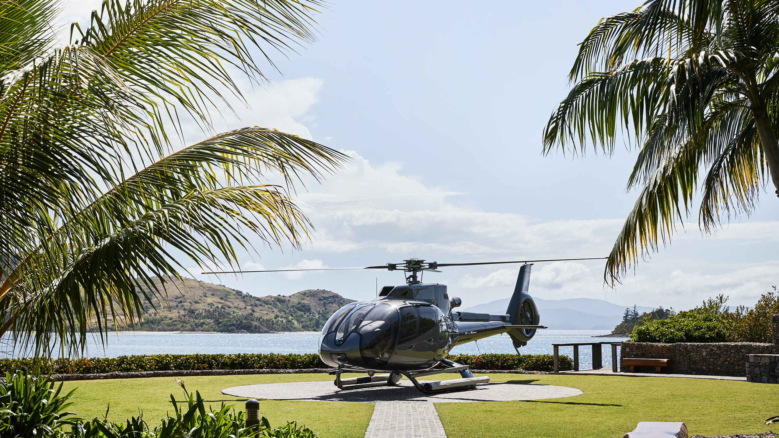 qualia resort helicopter on private helipad surrounded by palm trees and Whitsunday views