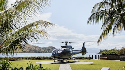 qualia resort helicopter on private helipad surrounded by palm trees and Whitsunday views